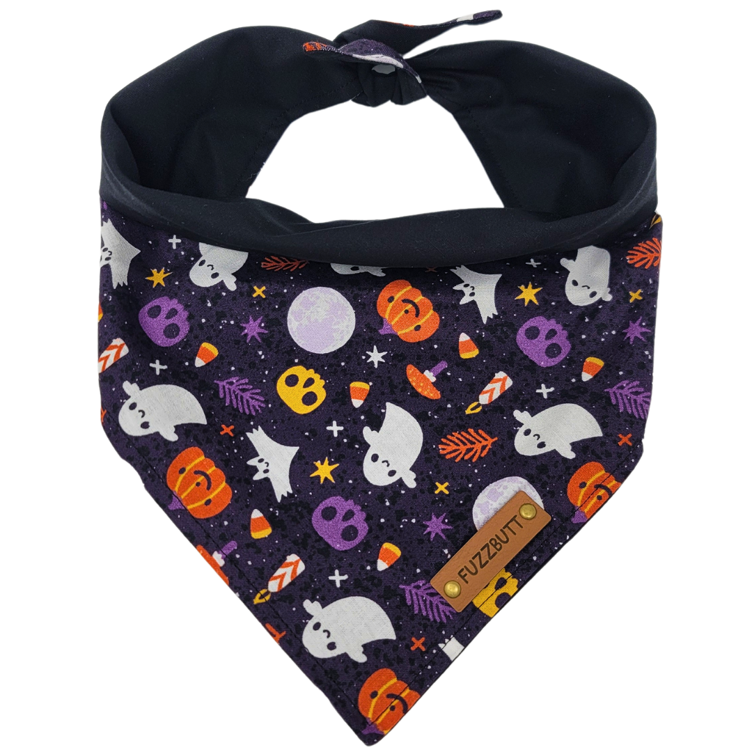 front view of a handmade Halloween dog bandana or handmade Halloween cat bandana with colorful skulls, ghosts, spiders, candy corn and moons; this pattern is called Ghosts and Skulls